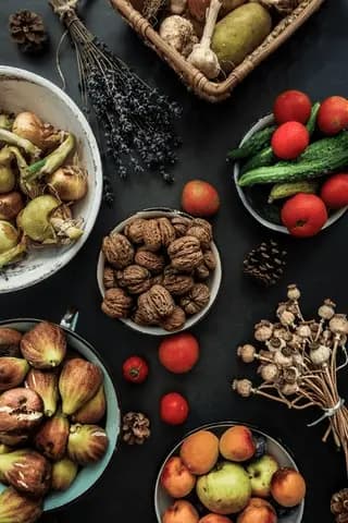 Svart bakgrund med olika skålar ovanifrån med olika frukter, grönsaker och nötter i dem